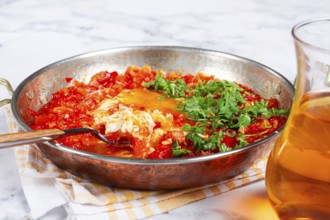 Traditional Turkish dish, scrambled eggs with tomatoes, Menemen, with herbs, in a frying pan,