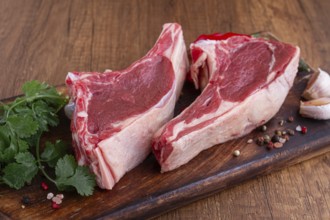 Freshly sliced lamb chops, with herbs and vegetables, on a wooden board, ready to cook, on a wooden