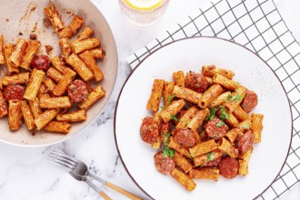 Rigatoni pasta with spicy sausage, and rich tomato sauce served, on a white plate, homemade