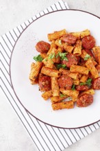 Rigatoni pasta with spicy sausage, and rich tomato sauce served, on a white plate, homemade