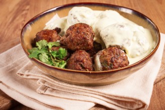 Swedish meatballs in cream sauce, plate on a wooden table, homemade, no people