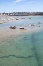 Over the shallow, turquoise water and moist sandy soil at low tide (low tide), with the shadows of