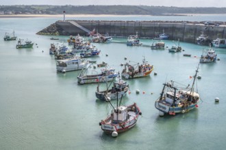 At low tide, numerous colorful, traditional fishing boats with netting equipment lie quietly moored
