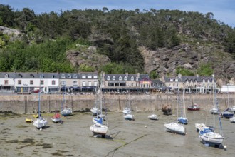 View of Erquy Bay at low tide with a fortified promenade behind which a series of bright,