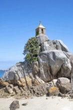 The small, historic Saint-Gildas chapel is perched on rugged, pink rock formations on the banks of