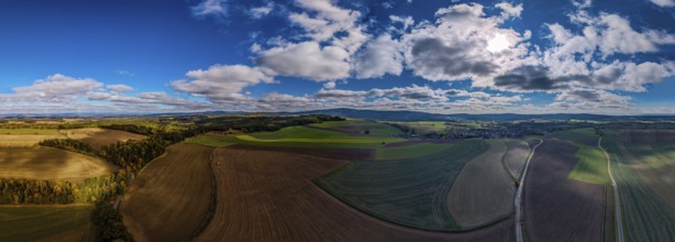 A breathtaking view of a green landscape with rolling hills and fields. The sky is blue with lots