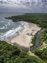 A sandy beach with a river flowing into the sea surrounded by forests. Aerial view to beautiful