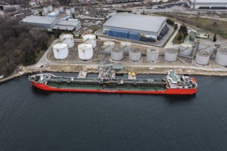 A tanker docked at a port next to large storage tanks