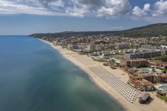 Aerial view of a long sandy beach stretching along a coastal city. Aerial view to a sea resort