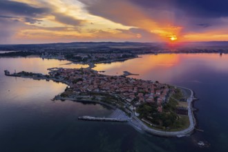Aerial view of a peninsula at sunset with an orange sky and calm sea. Aerial view to old town of