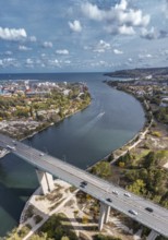 Aerial view of a bridge with cars spanning a winding river within an urban landscape. Aerial view