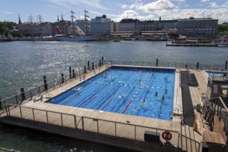 HELSINKI, FINLAND - JULY 6 2024: People enjoying public sea swimming pool and traditional sauna on