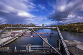 The view shows a lock on a calm body of water. The autumn colors of the trees are reflected in the
