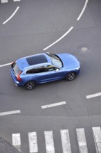 Blue unrecognizable car moving on road with broken line near pedestrian crossing, driverless