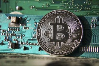 Silver bitcoin coin in front of computer motherboard, cryptocurrency mining and investing concept