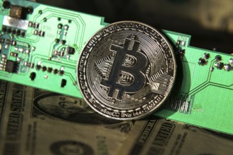 Silver bitcoin coin with dollars and computer motherboard, cryptocurrency mining concept Prague