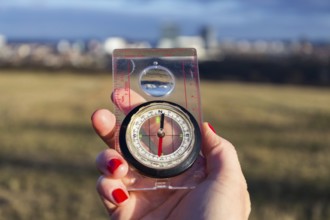 Female hand holding glass compass, nature in background, sunny autumn day, life change and new