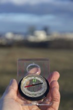 Male hand holding glass compass, nature in background, sunny autumn day, life change and new years