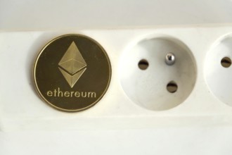 Ethereum coin lying on power strip extension cord with empty socket, cryptocurrency energy