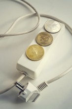 Bitcoin, Ethereum and Ripple coins lying on power strip extension cord with 3 sockets, largest