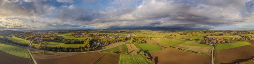 The picture shows a picturesque landscape with rolling hills, fields and forests during a colorful
