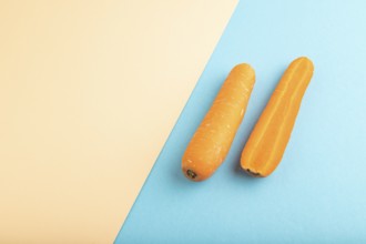 Orange Carrot on orange and blue pastel paper background. Side view, copy space, flat lay. healthy