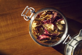 Dried apples and pears in open glass jar lying on wooden table, organic fruit food, healthy