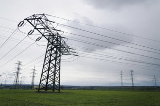 Electricity pylons conducting current from distribution power station with dramatic cloudy sky copy
