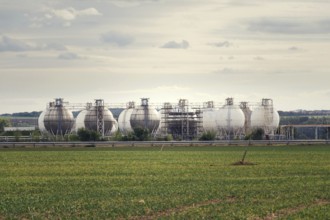 Liquid and fluid gas holder storage, sphere shape container tanks, green field in foreground Prague