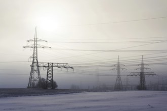 Electricity pylons from distribution power station in foggy winter freeze Prague Czech republic