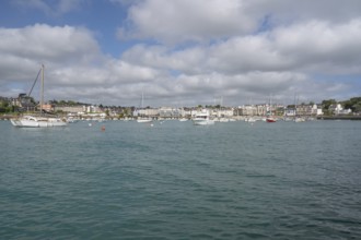 A series of small sailboats, probably optimists, with red and white ringed sails, move in formation