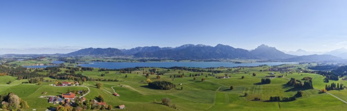 Panoramic view of a vast landscape with Lake Forggensee and mountains on the horizon, near Füssen,
