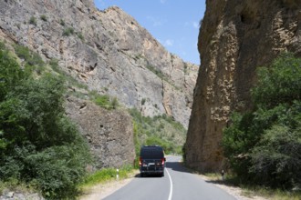 Road through rocky landscape with a black van, camper drives through the Amaghu Gorge from Noravank