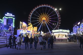 Oktoberfest visitors at night with the Ferris wheel in the background, Munich, Bavaria, Germany