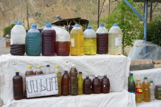 Various juices in plastic bottles at a rural market with mountain scenery, selling wine in Areni
