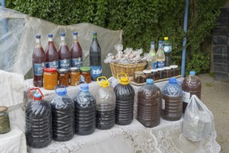 Market stall with various homemade products in bottles and glasses, selling wine and food in Areni