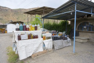 Market stand full of plastic bottles under a covered area selling wine and food in Areni village,