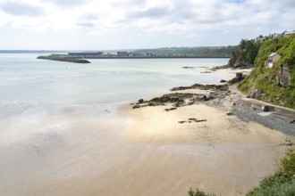 The view over a wide sandy and pebble beach at low tide towards the distinctive Port du Legue