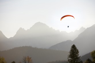 Paraglider at sunset over mountains surrounded by a peaceful atmosphere, Schwangau, Ostallgäu,