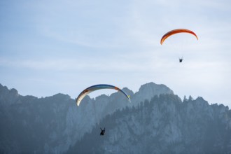 Two paragliders soar synchronously over a rocky mountain landscape, Schwangau, Ostallgäu, Allgäu,