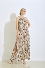 A woman stands confidently wearing a fashionable long dress featuring a unique pattern. She poses