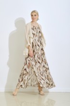 A stylish woman walks confidently in a beautiful, flowing dress with a unique pattern. The bright