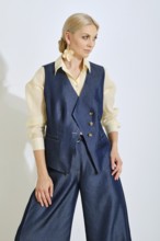 A model showcases a stylish blue vest paired with wide-leg pants and a light shirt. The outfit