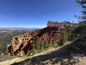 Majestic view of a canyon with red rocks and trees under clear skies, Bryce Canyon National Park is