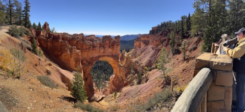 Visitors look at a majestic rock arch from a vantage point in the canyon, Bryce Canyon National