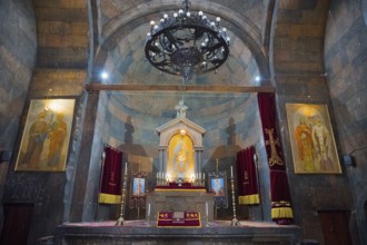 The church altar is decorated with icons and candles, framed by vaults and paintings, Khor Virap