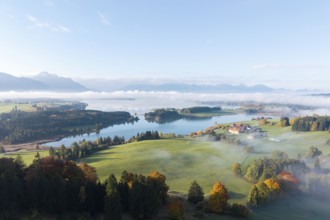 A vast landscape with the Forggenssee, surrounded by autumnal forests, near Roßhaupten, Ostallgäu,