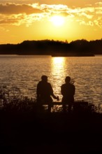 Two men sitting on a bench at sunset at Lake Gudelack, Lindow (Mark), Stechlin-Ruppiner Land nature