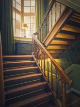 A vintage, wooden staircase with classic balusters leads up to a soft light that filters through