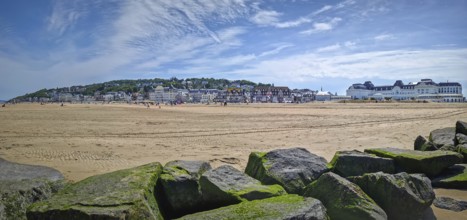 Panoramic view of Trouville-sur-Mer sandy beach, Normandy, France. Large, moss-covered breakwater